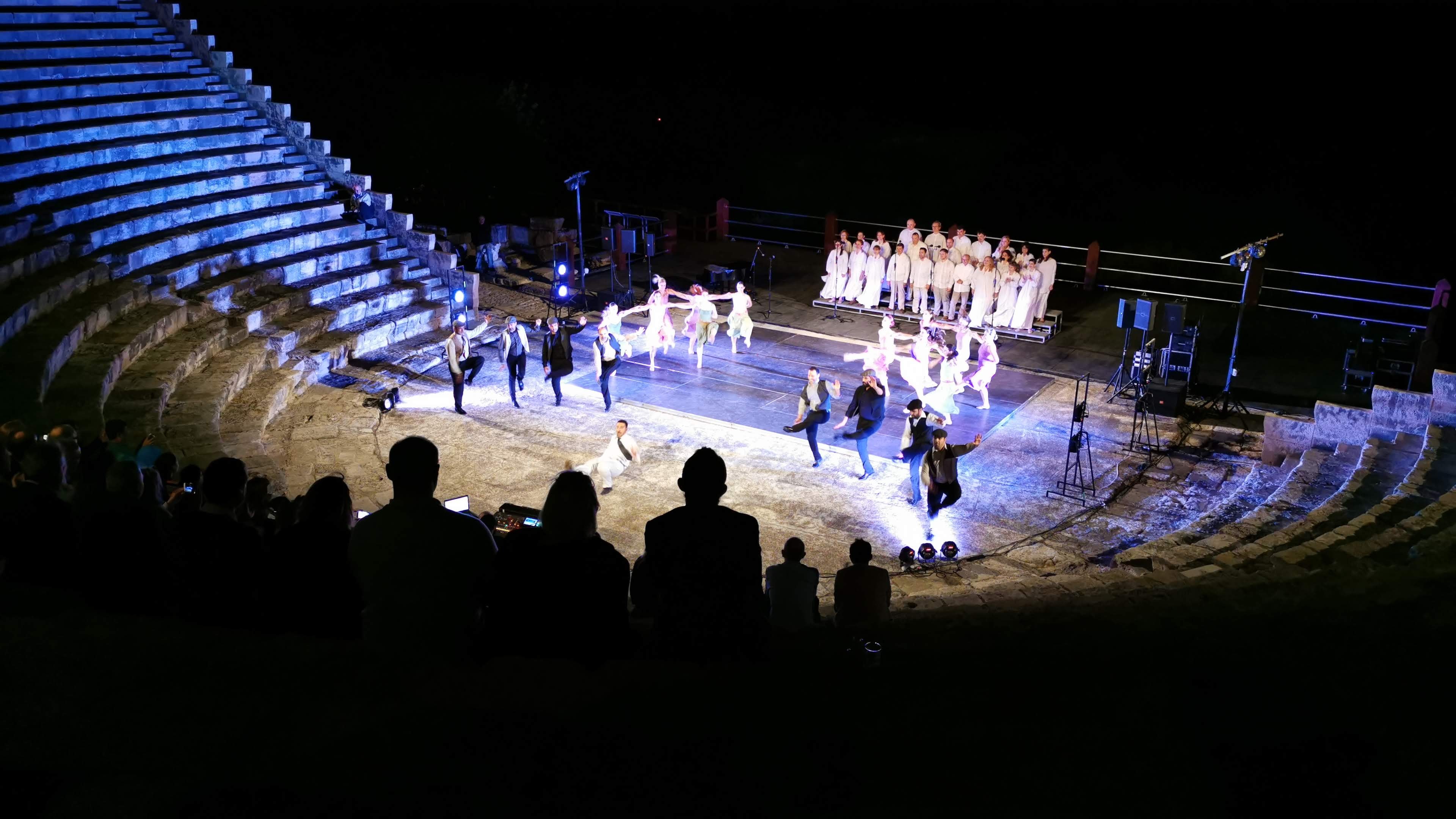 Dancers and choir performing under blue stage lights